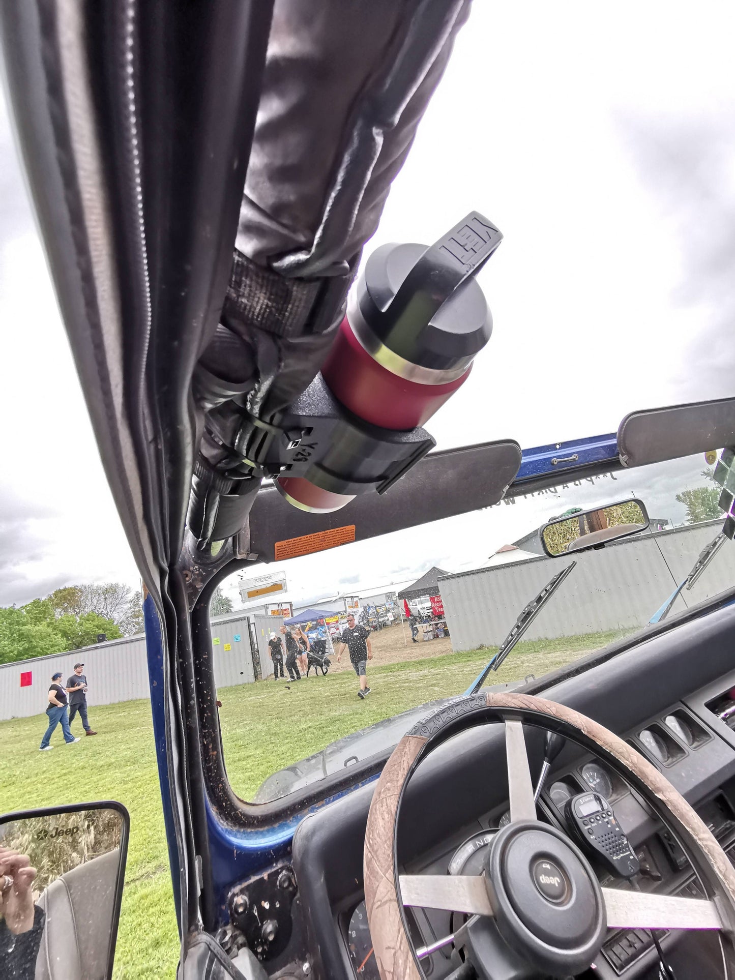 Jeep YJ interior with water bottle holder mounted to roll bar, securing red bottle, perfect for off-road hydration with top down.