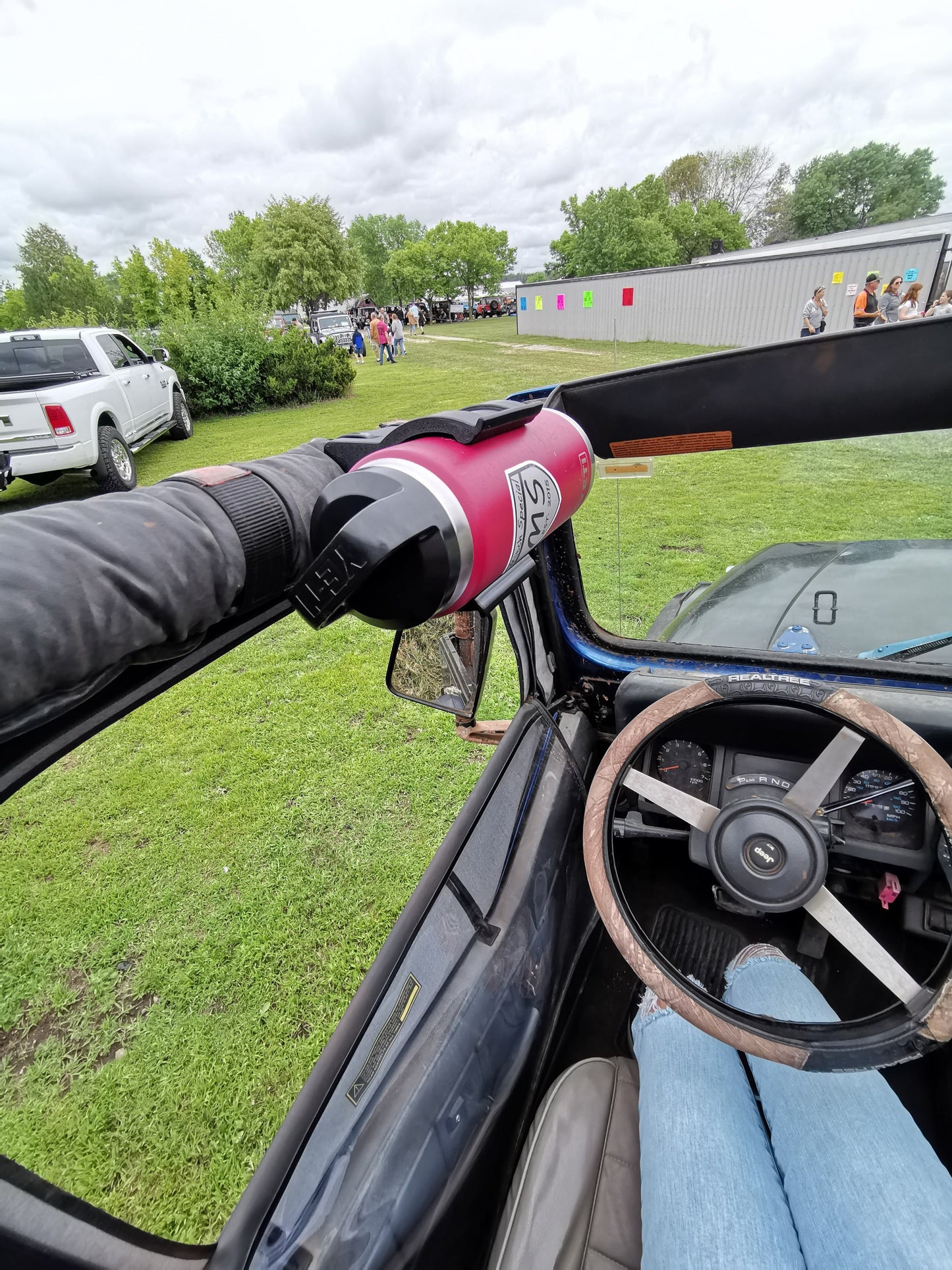 Jeep YJ water bottle holder securely mounted to the roll bar, holding a red bottle, designed for off-road adventures.