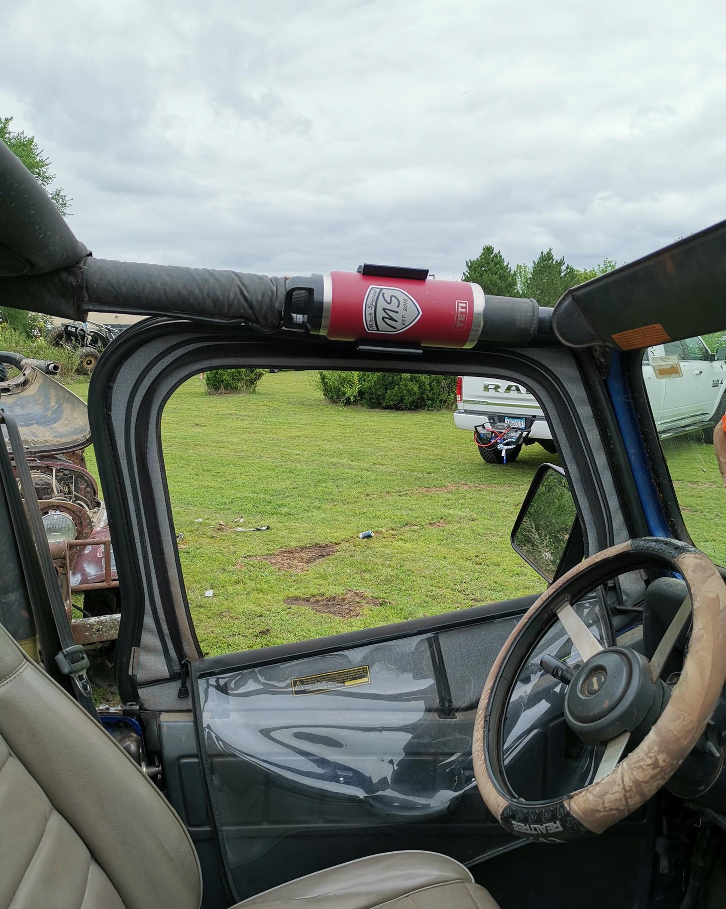 Jeep YJ water bottle holder mounted to roll bar, featuring a secure design with a red bottle, perfect for rugged off-road use.