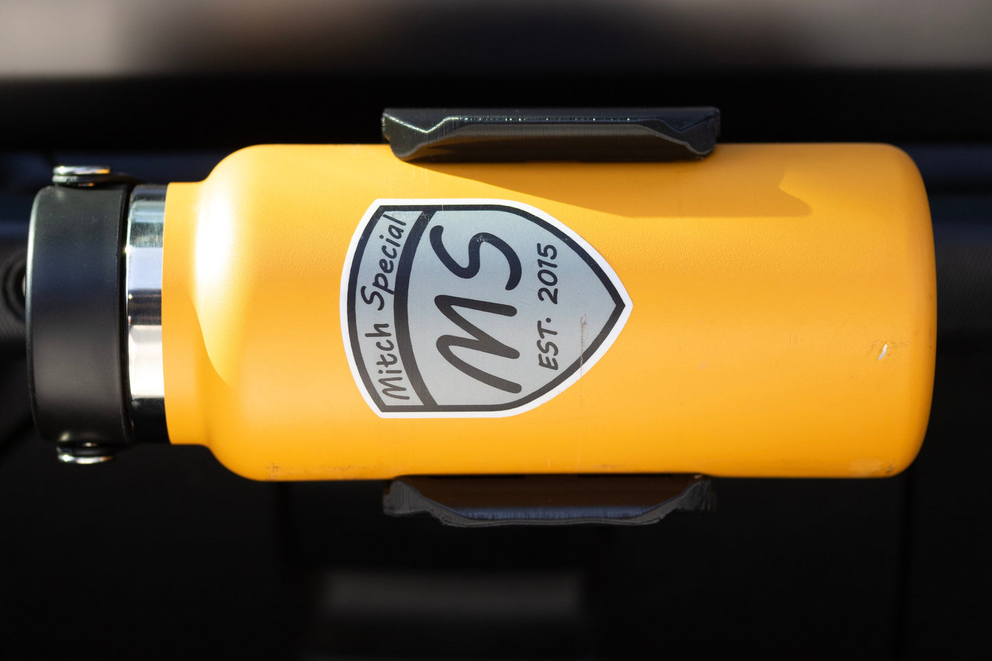 Close-up view of Water Bottle Holder for Jeep JL mounted to grab handle from passenger seat perspective, highlighting its sturdy construction and secure water bottle fit