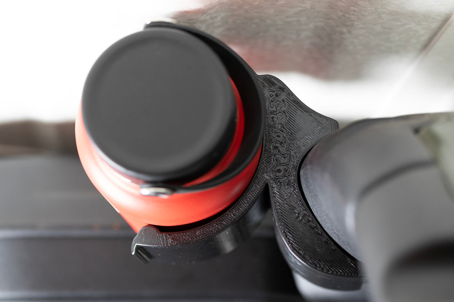 Jeep JL water bottle holder seamlessly fitting the contour of the roll bar, securely holding a red bottle for off-road use.