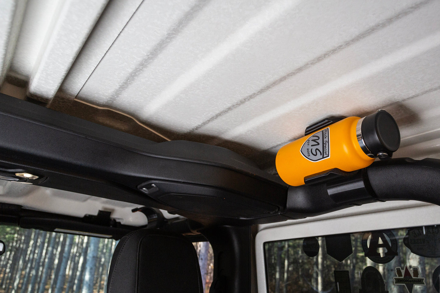 Image of Jeep JL rear roll cage water bottle holder, showcasing its space-saving design, with the water bottle tucked snugly against the roll cage, maximizing interior space and minimizing obstruction.