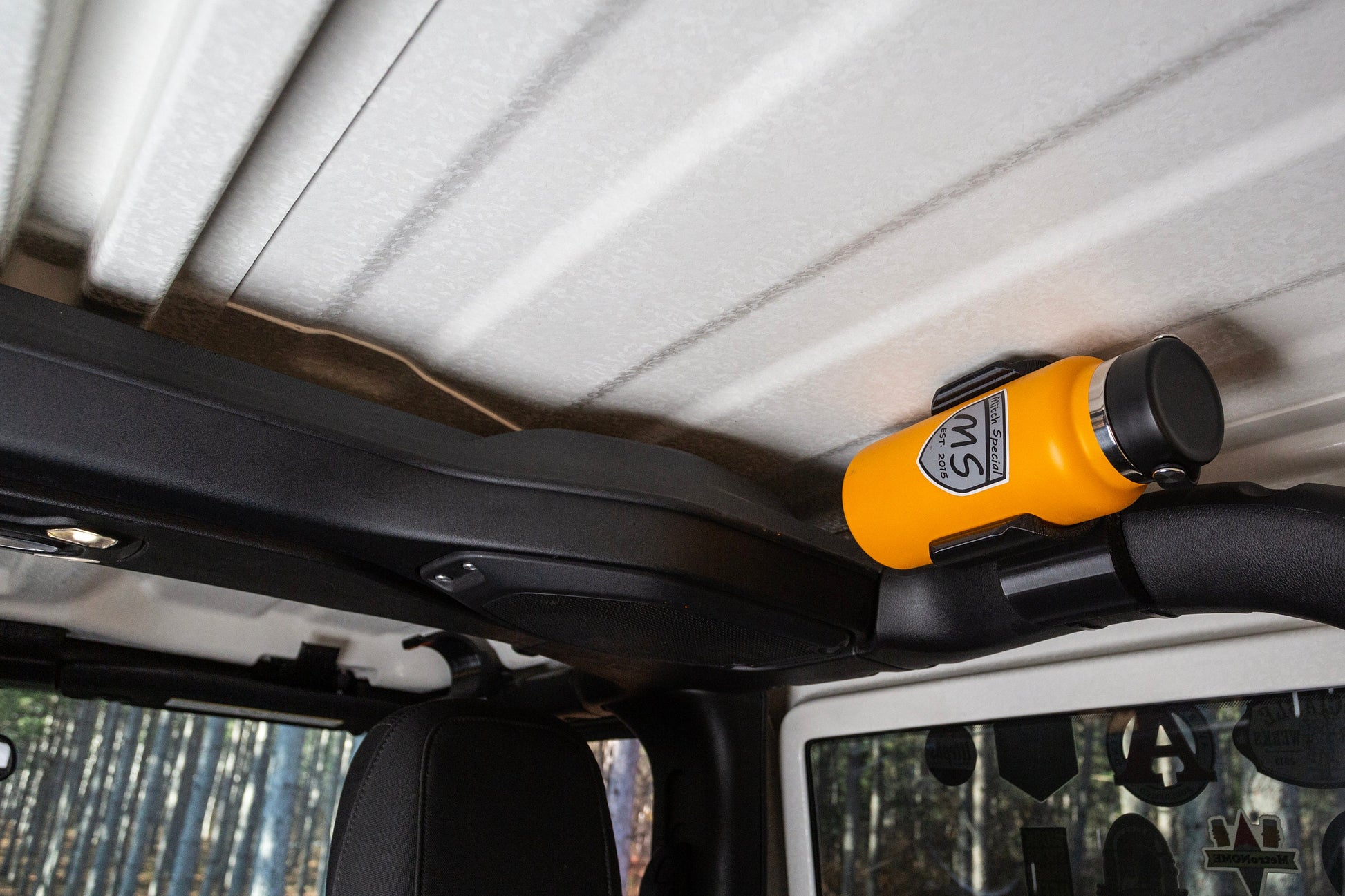 Image of Jeep JL rear roll cage water bottle holder, showcasing its space-saving design, with the water bottle tucked snugly against the roll cage, maximizing interior space and minimizing obstruction.