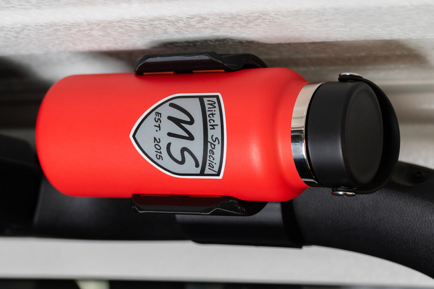 Jeep JL with water bottle holder mounted on the roll bar near the roof, securing a red water bottle for off-road adventures.