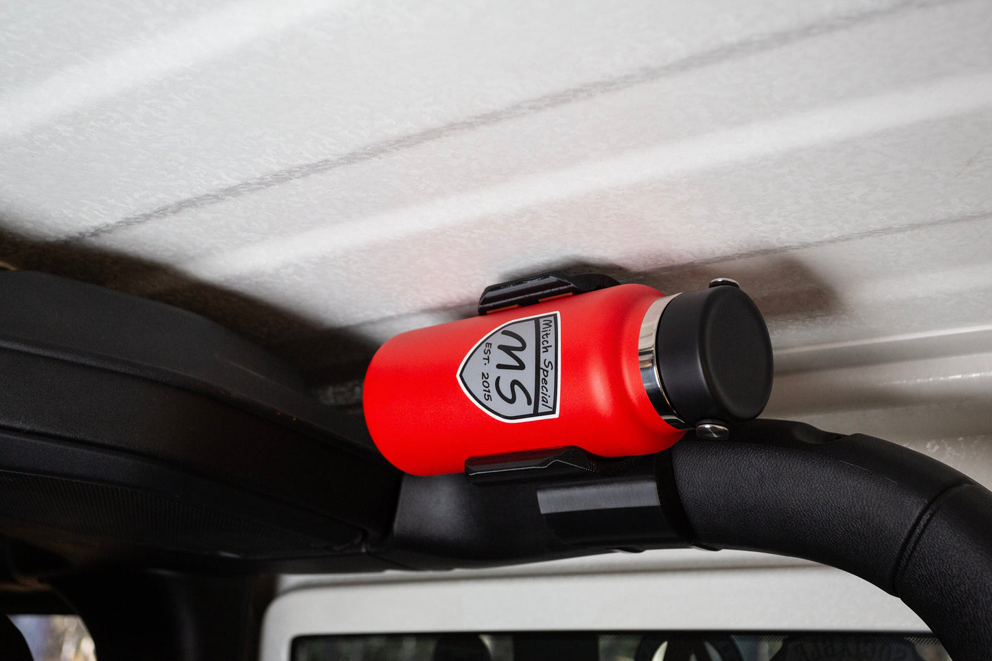Jeep JL with red Mitch Special water bottle mounted on roll bar. Secure holder, ideal for off-road adventures.