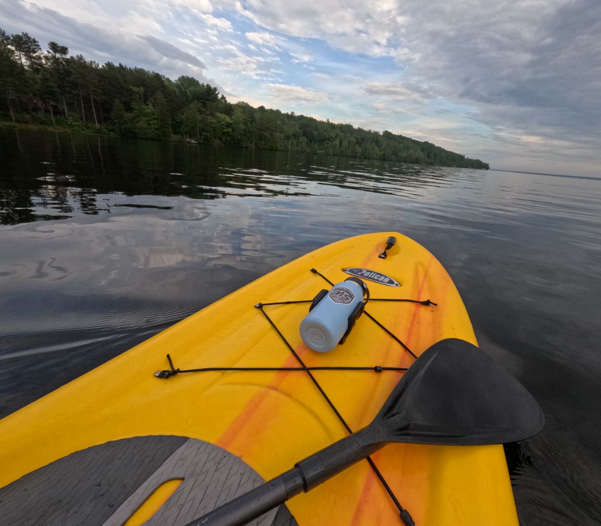 Serene lake scenery with paddleboard and water bottle holder installed, showcasing secure and convenient hydration solution for paddleboarding enthusiasts