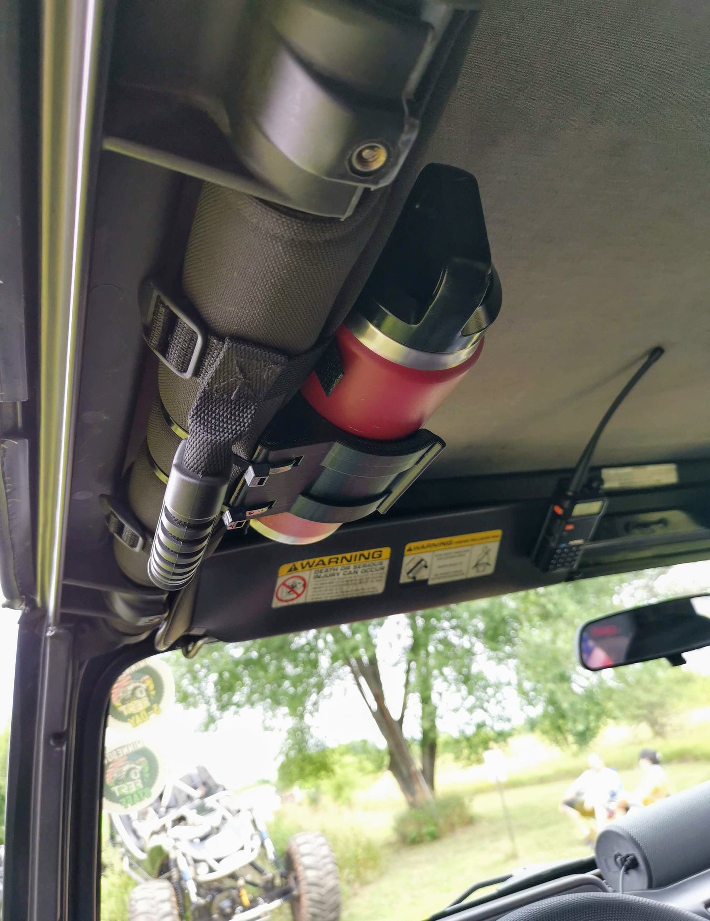 Jeep Wrangler interior showing a roll bar-mounted water bottle holder, designed for off-road use, compatible with TJ models.