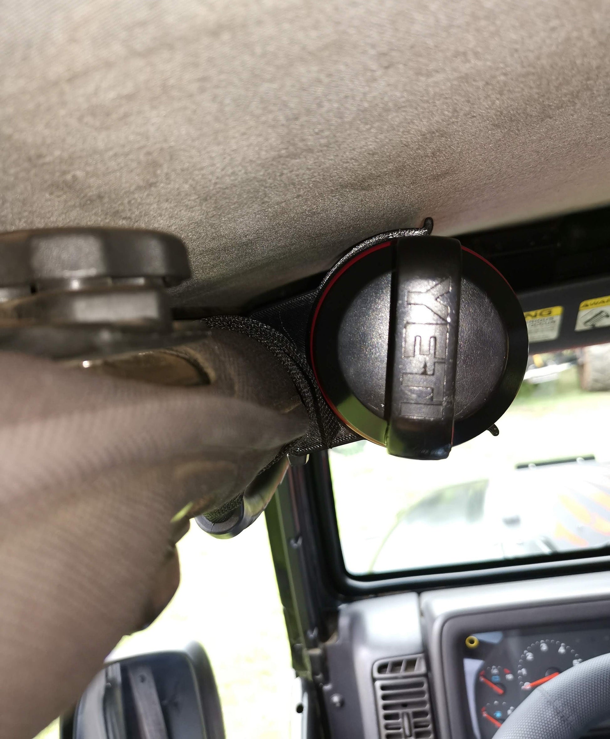 Close-up view of a Jeep Wrangler TJ/LJ roll bar-mounted water bottle holder, securely holding a metal water bottle, ideal for off-road storage solutions.