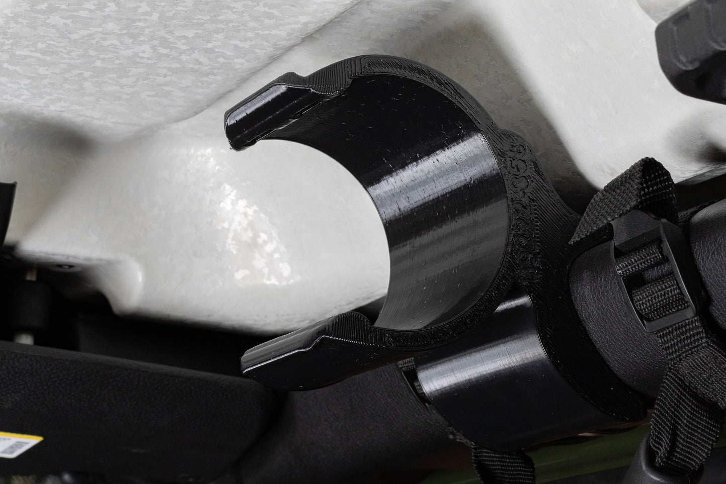 Close-up image of an empty water bottle holder mounted to the front roll bar of a Jeep JL, viewed from a rear angle, showcasing its contoured design that seamlessly follows the roll bar's curvature, positioning the holder high and out of the way for optimal clearance.