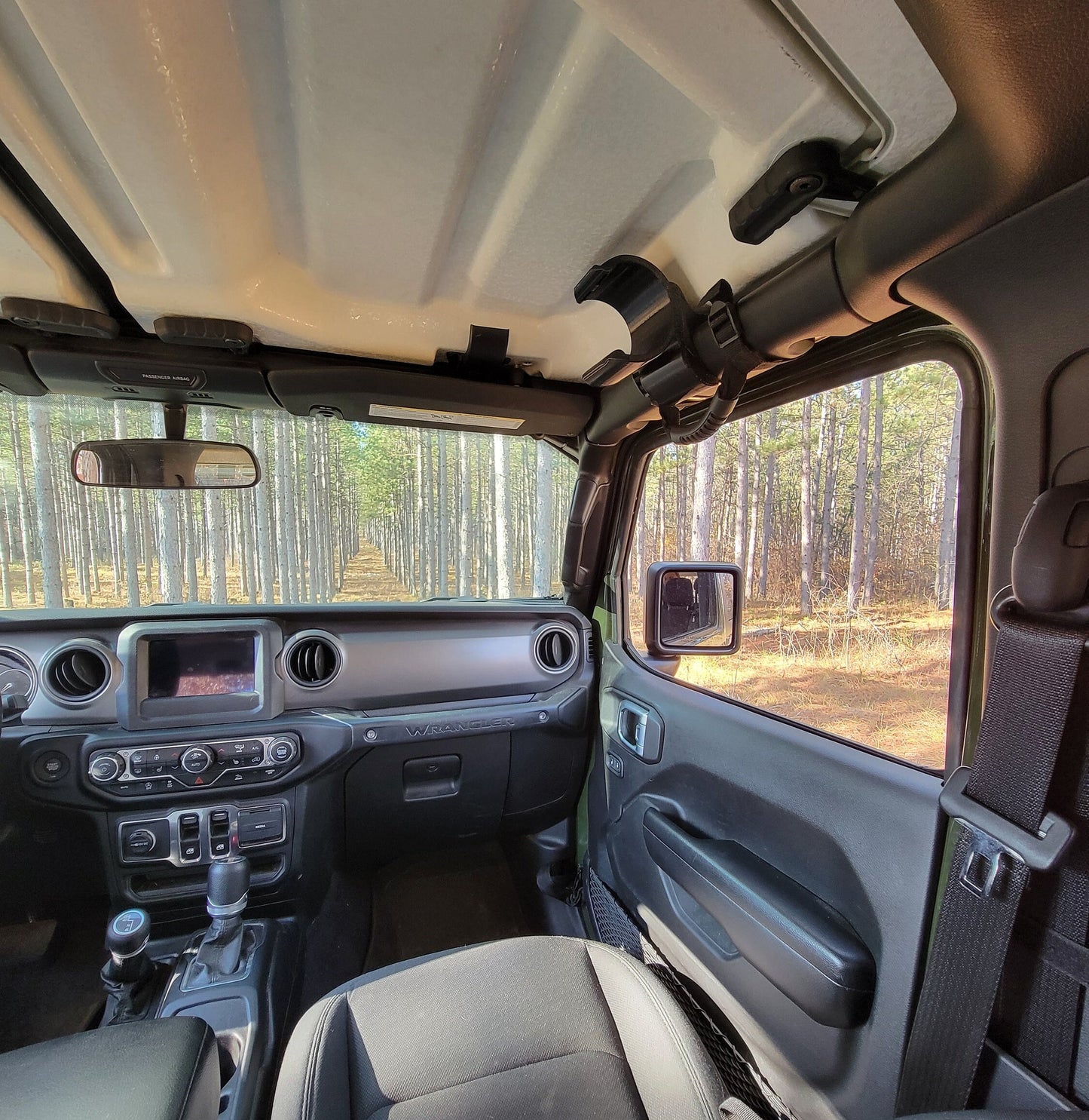 Passenger-side view of an empty water bottle holder mounted to the front roll bar of a Jeep JL, showcasing its sleek design and convenient location from the passenger's perspective.