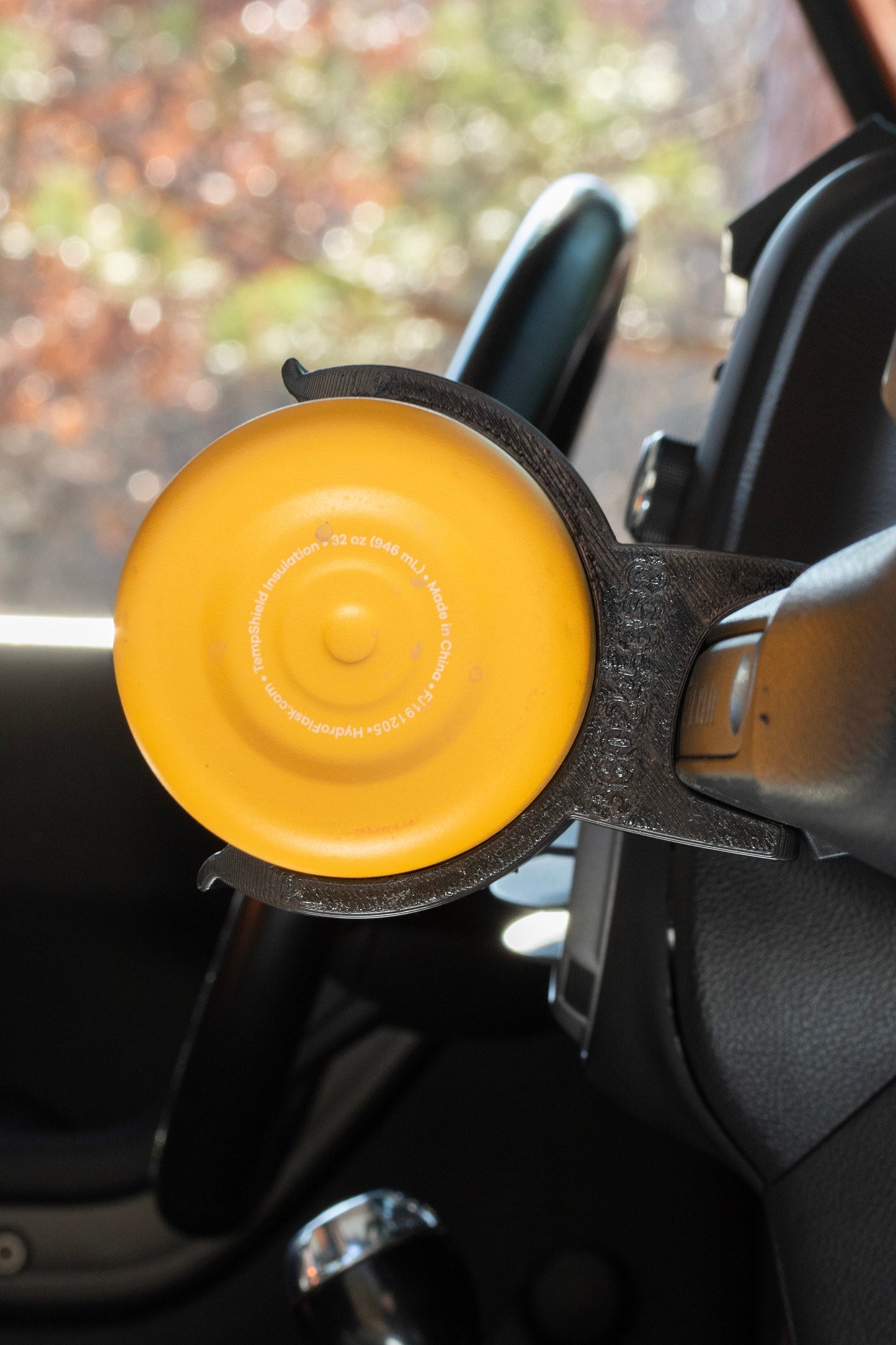 Side view close-up of a yellow water bottle in a holder mounted to the passenger grab handle of a Jeep JK, showcasing the secure and precise fit of the holder for off-road convenience and style.