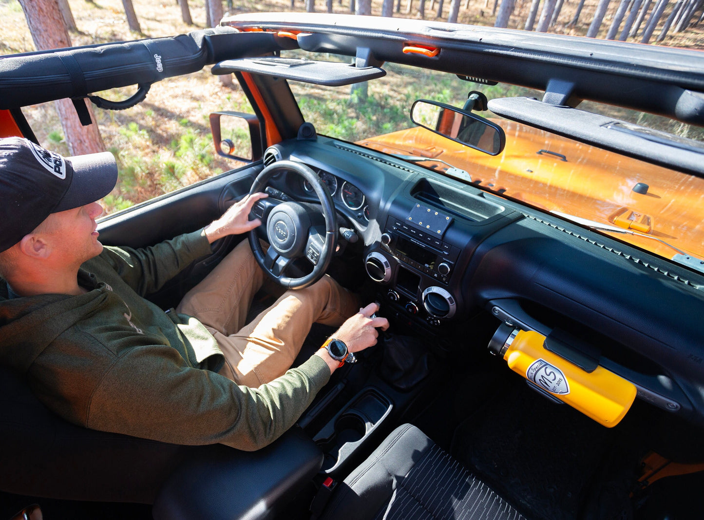 Water bottle mounted in a holder on the passenger grab handle of a Jeep JK, with a clear view of the driver seat, showcasing  easy accessibility of the water bottle for the driver—perfect Jeep accessory for convenience and off-road adventures.