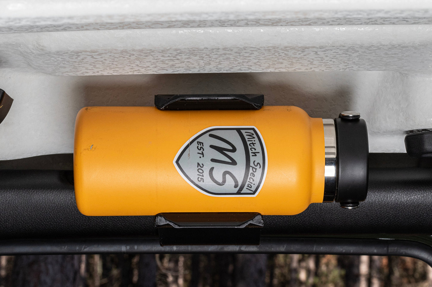 Close-up image of a sleek water bottle holder mounted to the front roll bar of a Jeep JL, showcasing its slim design that doesn't encroach on the door opening, providing easy access and clearance