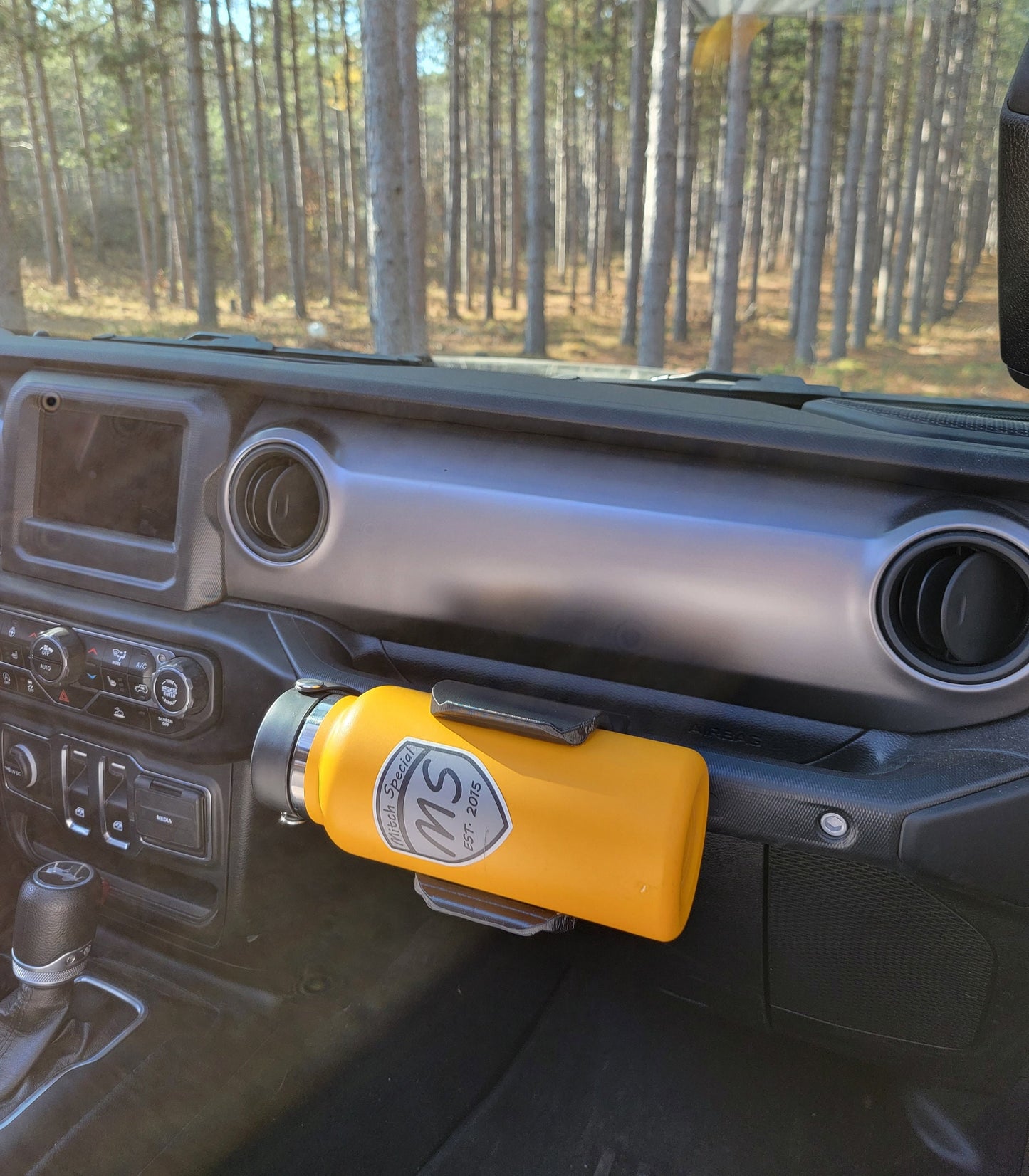 Passenger side view of Jeep JL water bottle holder mounted to grab handle, demonstrating its space-saving design and ergonomic placement, allowing for easy entry and exit without obstruction