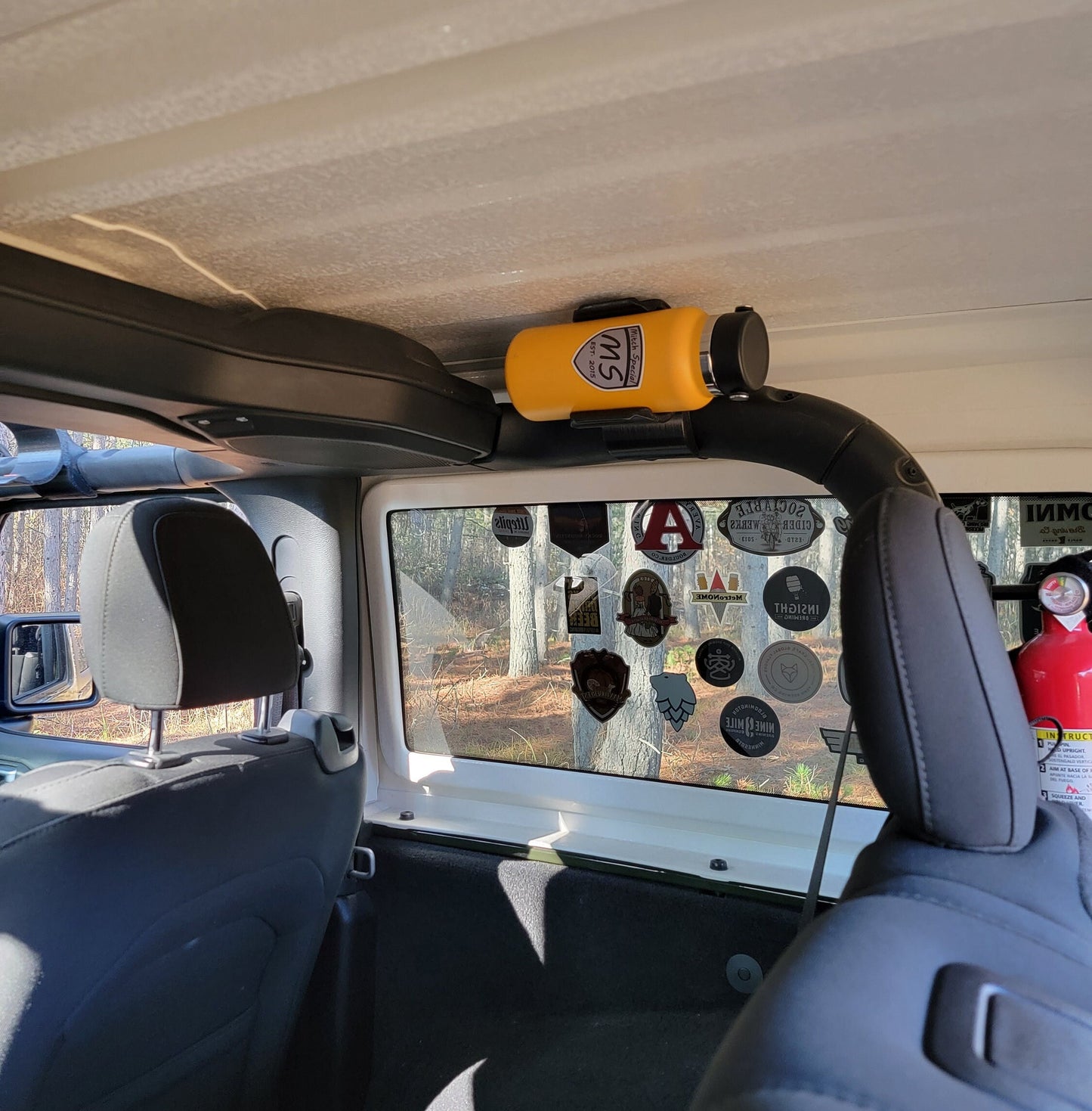 Image of Jeep JL interior, showing a water bottle holder seamlessly integrated into the rear roll cage, providing a cohesive and factory-like installation that complements the vehicle's design.