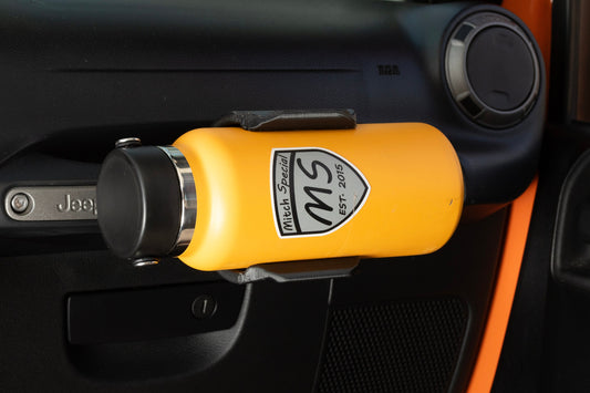 Yellow water bottle with a 'Mitch Special' logo held in a custom grab handle-mounted holder inside a Jeep Wrangler, showcasing a convenient accessory for Jeep interiors.