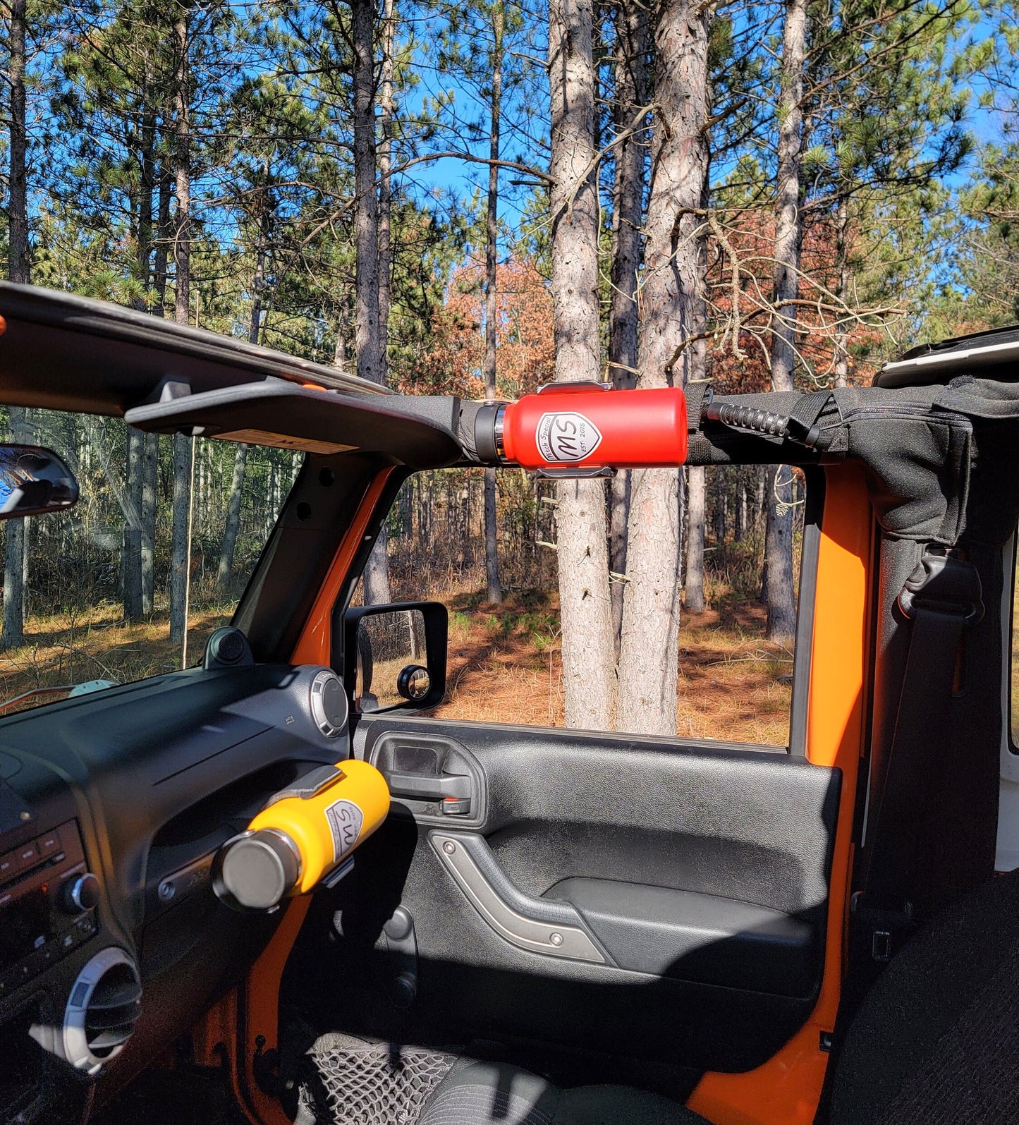 Photo of Jeep JK in outdoor setting, roofs removed, featuring rugged water bottle storage: heavy-duty roll bar holder and sleek grab handle holder, perfect for trail-blazing enthusiasts.