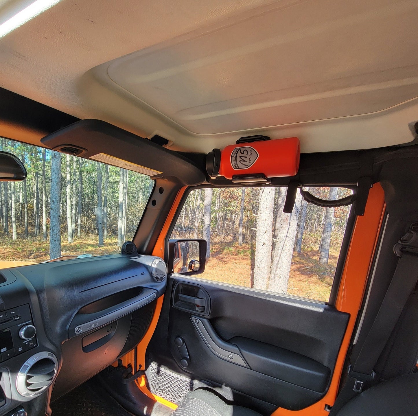 Jeep JK interior with HD water bottle holder installed on roll bar, providing easy access to hydration while maintaining passenger space.